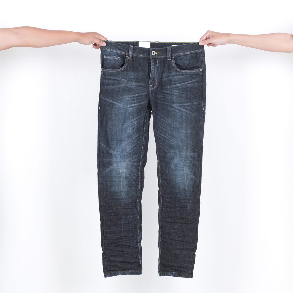 Deux coupes de jeans, droite et slim, présentées sur un portant dans un magasin de vêtements.