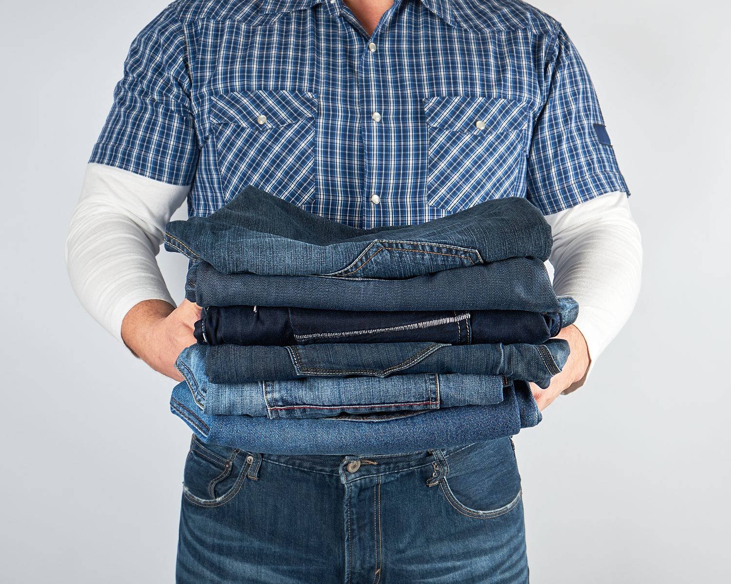 Homme comparant un jean droit et un jean slim devant un miroir en boutique.