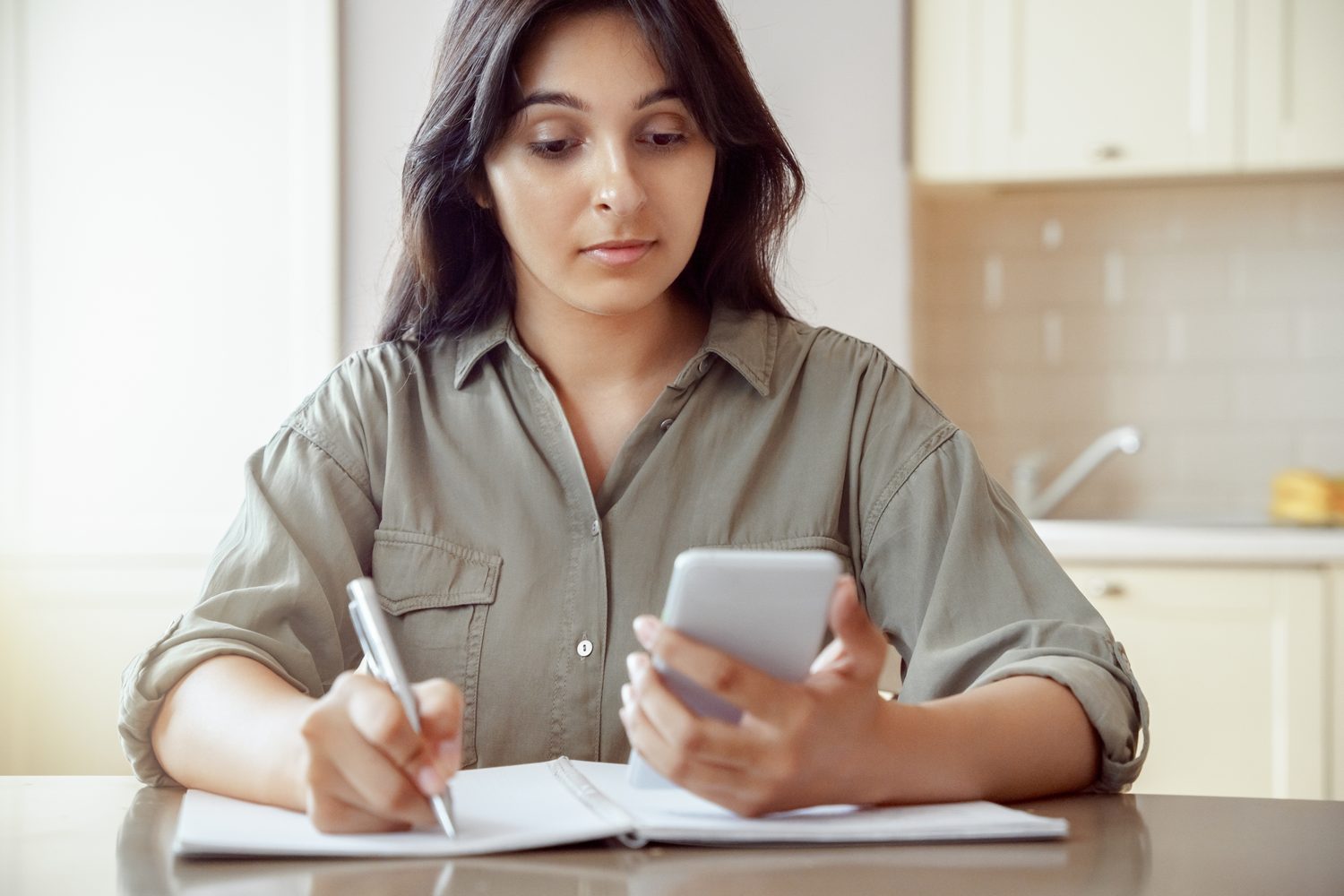 Femme comparant un agenda papier et le calendrier affiché sur son smartphone sur un bureau