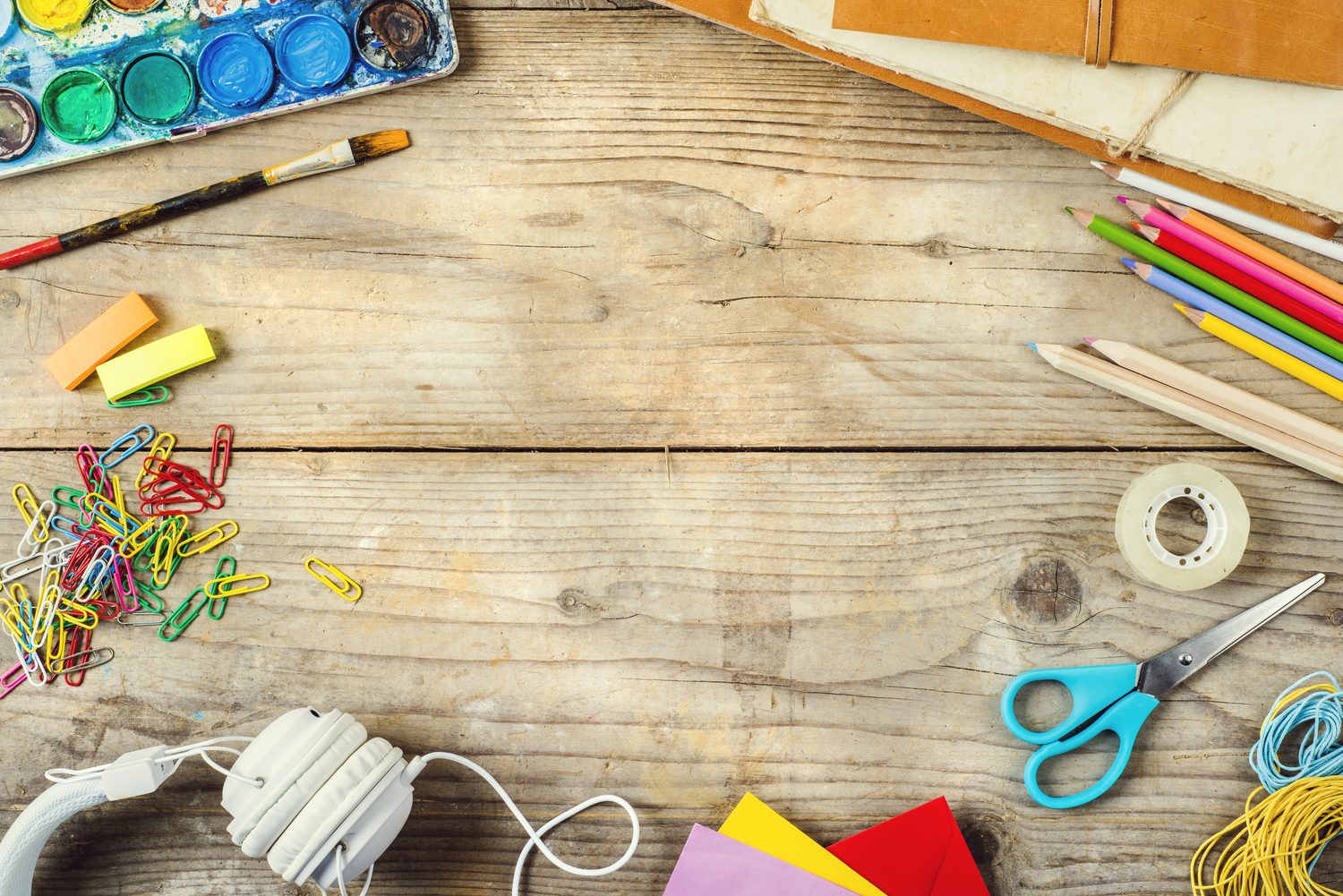 Table de loisirs créatifs avec papier coloré, ciseaux, colle et feutres prêts à l’emploi à la maison.