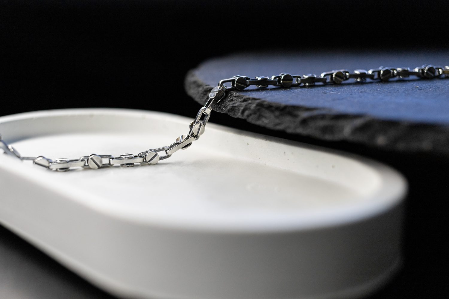 Une main nettoie délicatement une chaîne en argent noircie avec un chiffon doux.