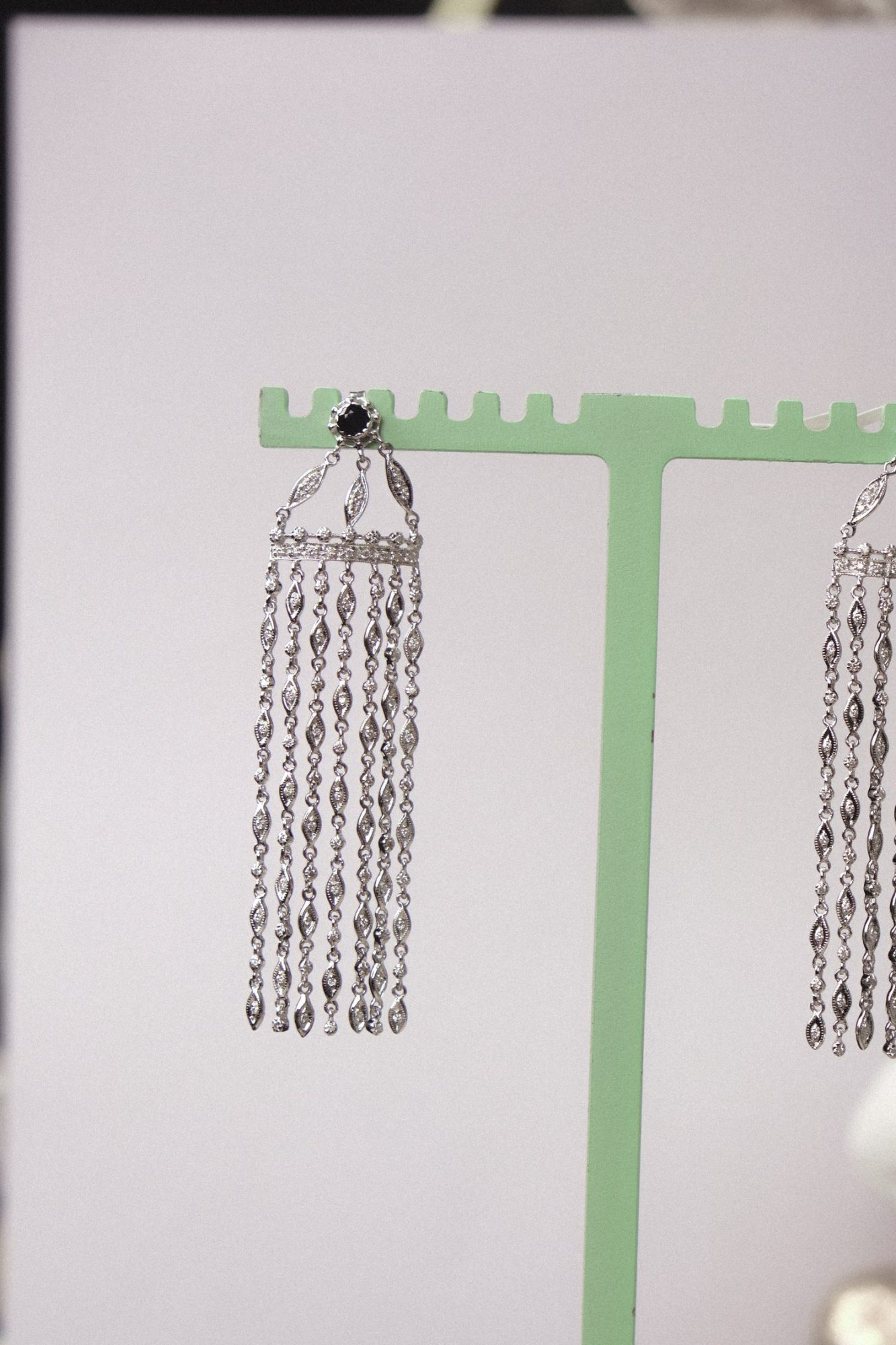 Bracelet et collier en acier inoxydable portés sous la douche, avec des gouttes d’eau visibles sur la peau.