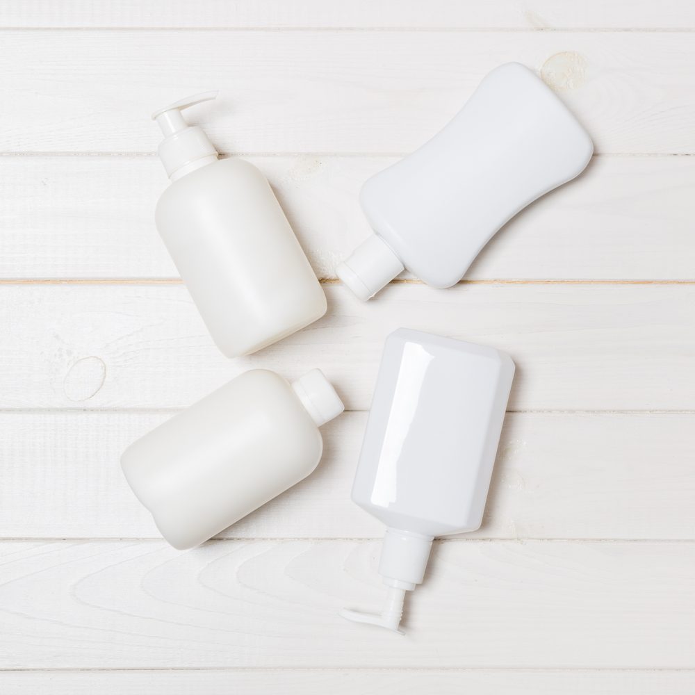 Deux types de shampoing, un pain solide et un flacon liquide, posés près d’un lavabo.