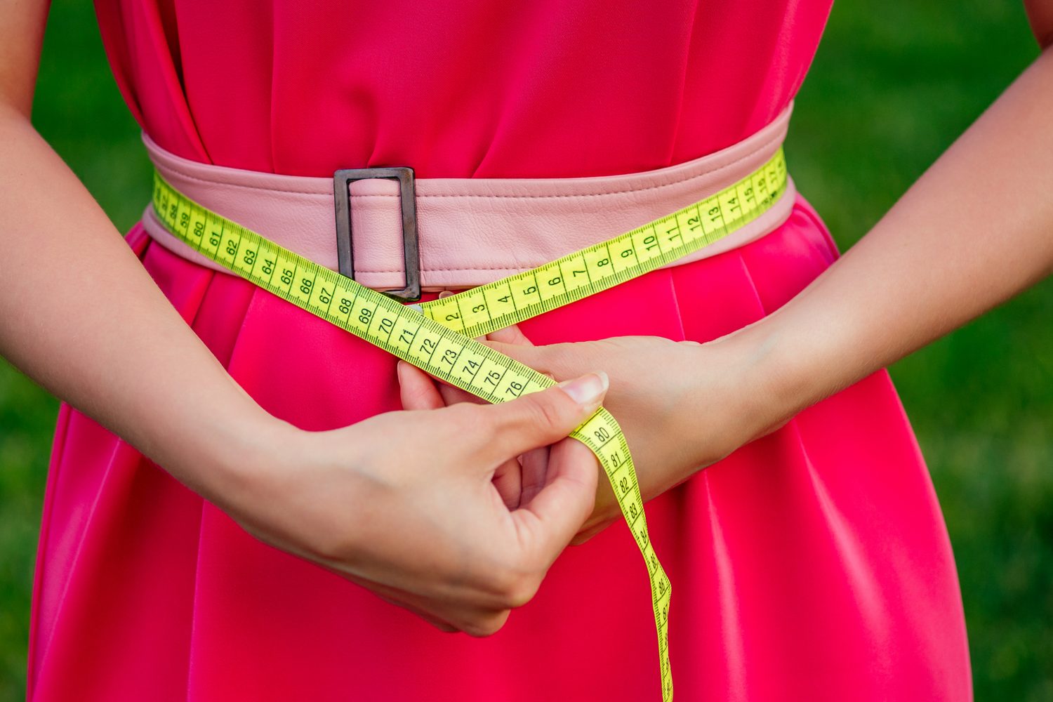 Personne mesurant son tour de taille avec un mètre ruban avant de choisir une ceinture.